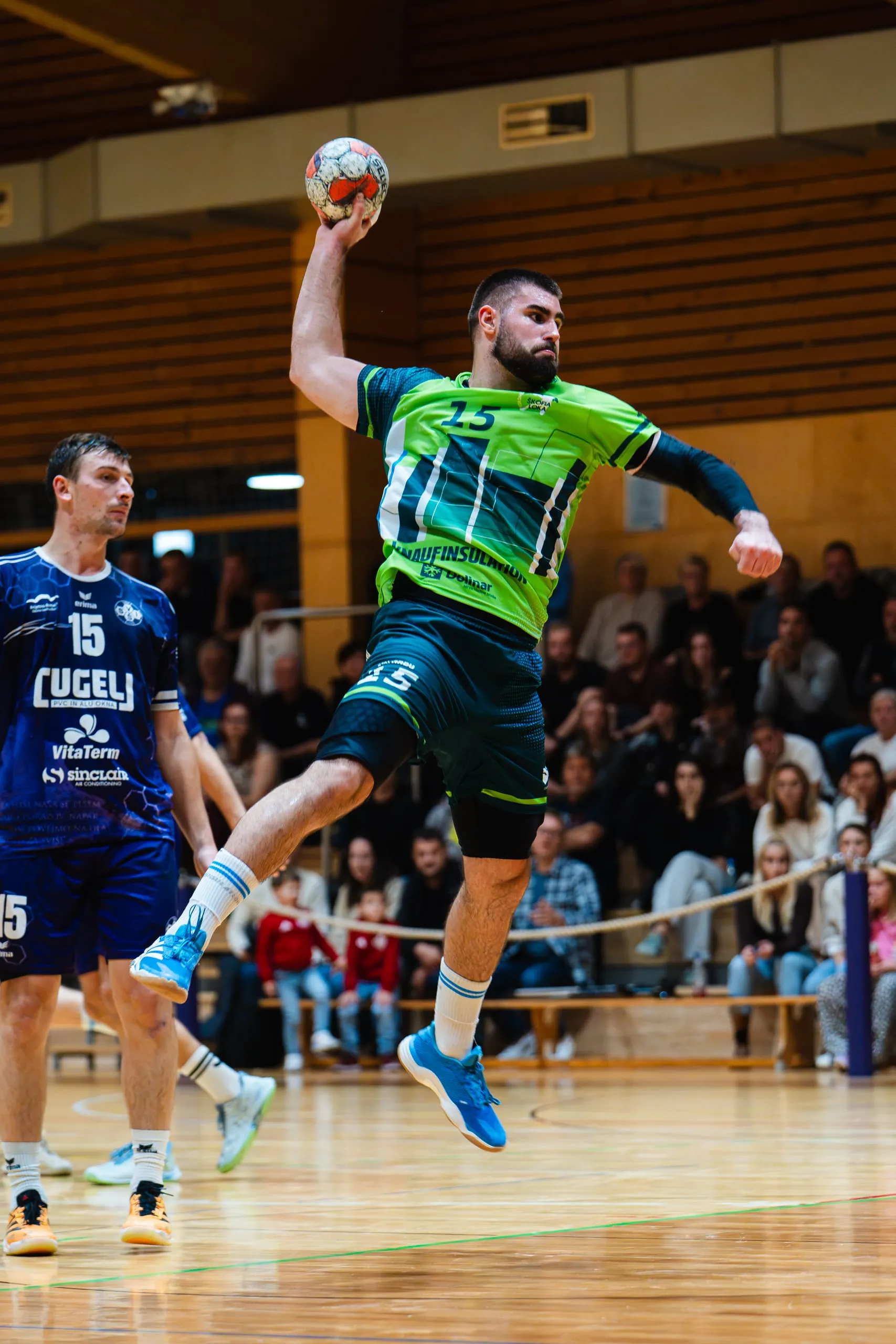 Igralec RD Škofja Loka s številko 15 v zelenem gostujočem dresu v skoku na strel proti RK Sviš