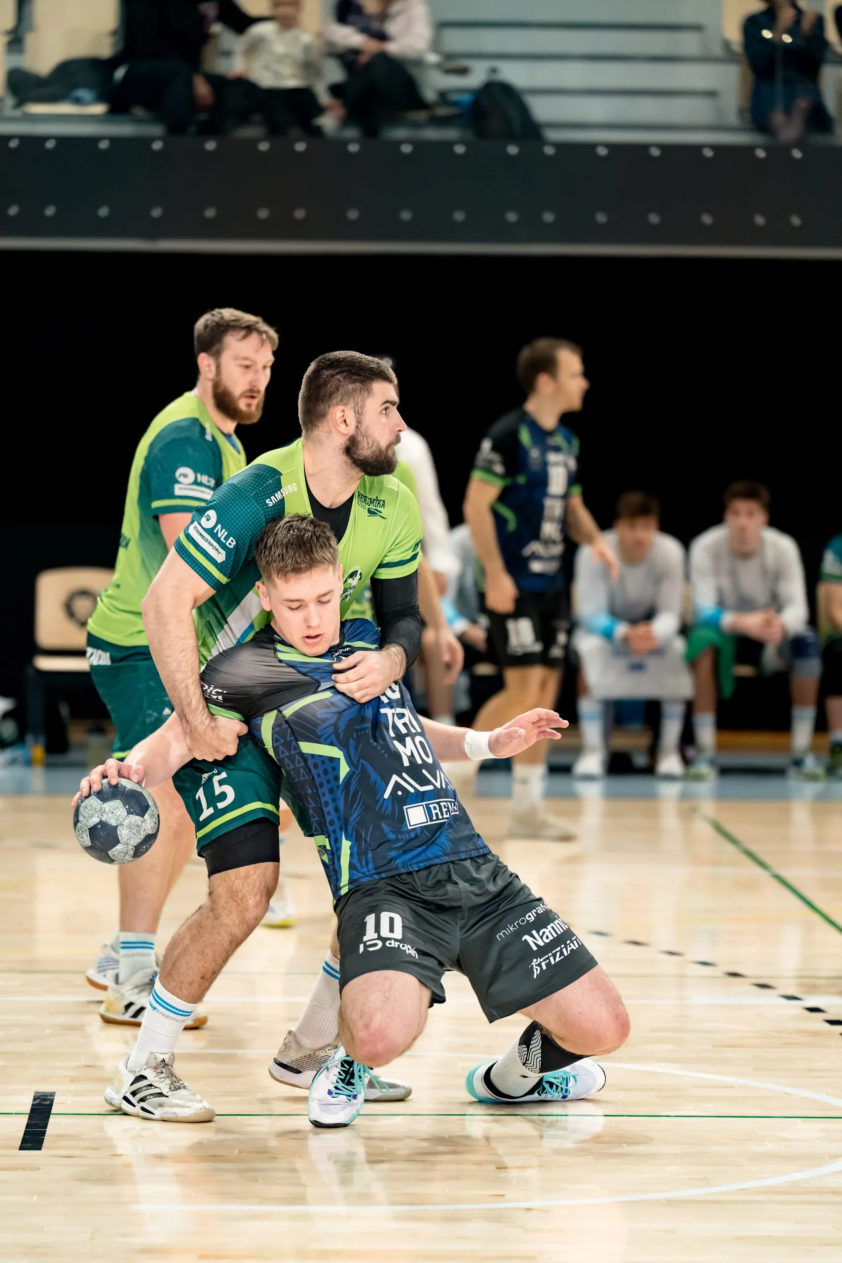 Igralca RD Škofja Loka s številkama 15 in 4 v zelenih dresih ustavljata napadalca RK Trimo Trebnje